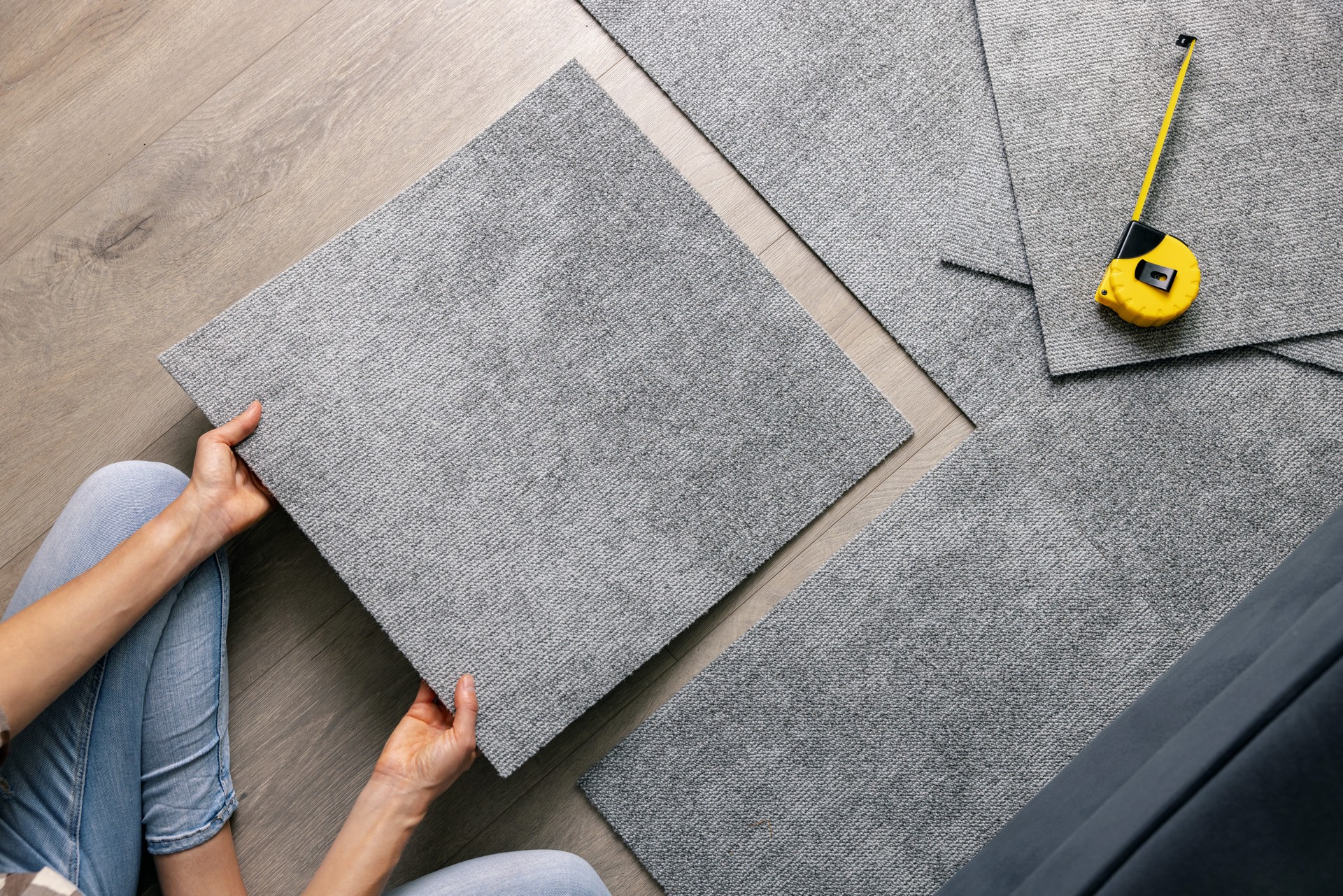 woman laying carpet tiles on floor in living room. diy home improvement